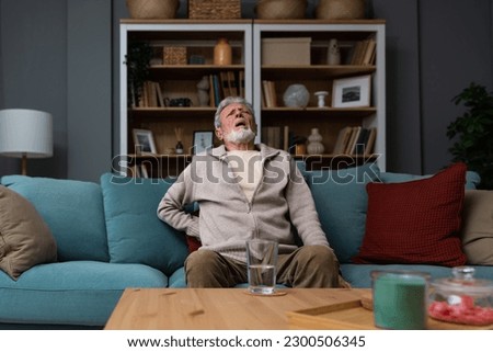 Aged grey haired senior red face man writhes in pain suffers from low back strain, touch rubbing or massaging loin reduces backache. Degenerative disk disease, pinched nerve rheumatism concept Royalty-Free Stock Photo #2300506345