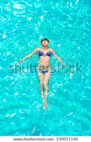 young girl floating in the pool outdoors