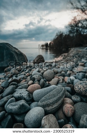 Close up of beach rocks on shore of Lake Ontario on cloudy evening. Royalty-Free Stock Photo #2300525319