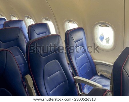 inside airplane many blue seats in row empty no people and aircraft ceiling with air conditioner buttons no smoking sign.travel trip concept, journey