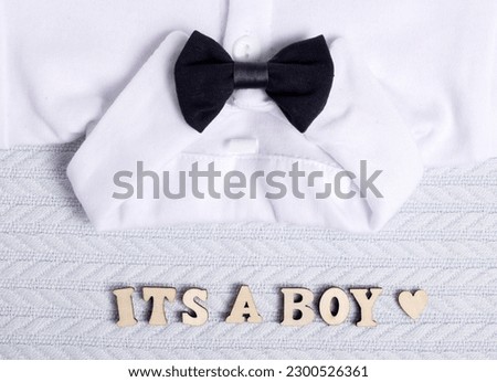 baby clothes, white bodysuit for boy with bow at collar, ultrasound scan and dry cotton branch meaning is natural textile.its a boy from wooden letters, blue blanket.clothes store for kids infant