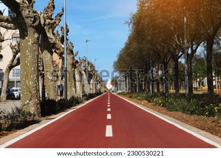 New red bikepath or pedestrian path separated by white line, traffic signs in the park. Bicycle path in European city, Spain. Two way cycle lane on an avenue. Urban traffic and transportation. Royalty-Free Stock Photo #2300530221