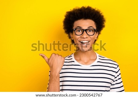 Photo of funny cheerful student guy direct finger empty space wear striped white black t-shirt isolated yellow color background