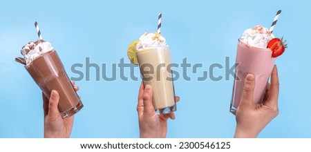 Set of summer refreshing milkshakes or smoothies with classic delicious taste - vanilla lemon, strawberry, chocolate, with whipped cream and toppings, On a white wooden light blue sunny background  Royalty-Free Stock Photo #2300546125