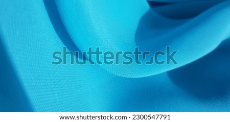 Wavy turquoise cyan translucent fabric in the sun, in folds (macro, blue crepe chiffon, texture).