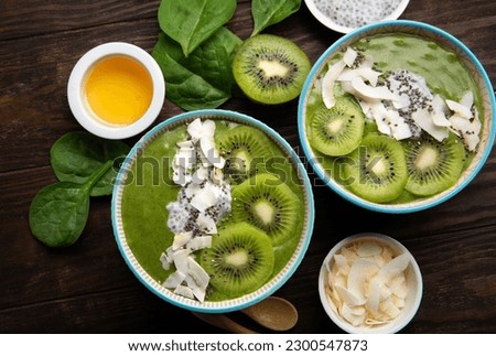 Green smoothie bowl with organic Spinach, Banana, Chia Seeds, fresh kiwi on dark wooden background. Vegan, Food and drink, healthy dieting and nutrition, alkaline, vegetarian concept. Royalty-Free Stock Photo #2300547873