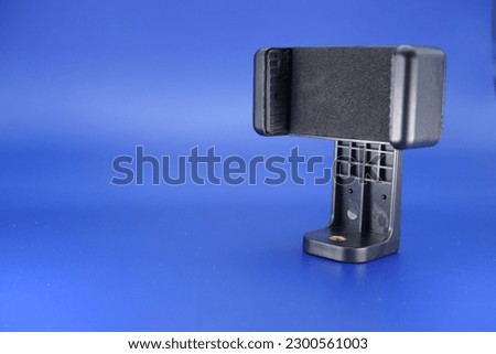 phone holder which is usually mounted on a tripod. phone holder isolated blue background.