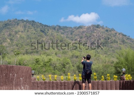 Male tourists stand to take pictures mountains and blue sky in the heat of the sun while traveling on vacation.