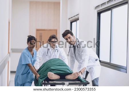 Doctors, Nurses, and Paramedics pushing stretcher gurney bed with seriously injured patient towards the operating room. Professional Staff Saving Lives. Health care Concept Royalty-Free Stock Photo #2300573355