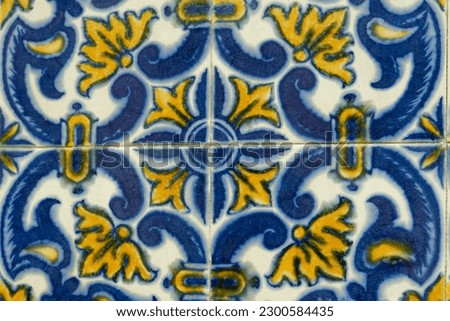 Floral ornate vivid coloured portugese tile texture in blue and yellow color outside on the wall in Portugal. Real antique tiling work.