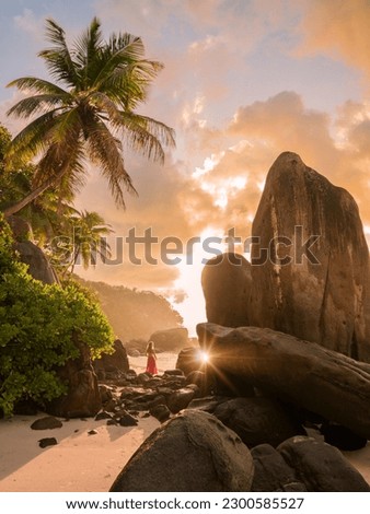 Beautiful sunrise over the ocean framed by scenic rocks and palm trees on the Seychelles island of Mahe, Anse Royale beach Royalty-Free Stock Photo #2300585527