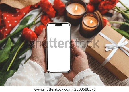 Mobile phone and spring flower tulips on a festive background. Theme of love, mother's day, women's day flat lay.