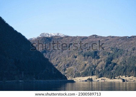 Fjord with mountains on horizon. Water glistens in the sun in Norway. Landscape photo from the north