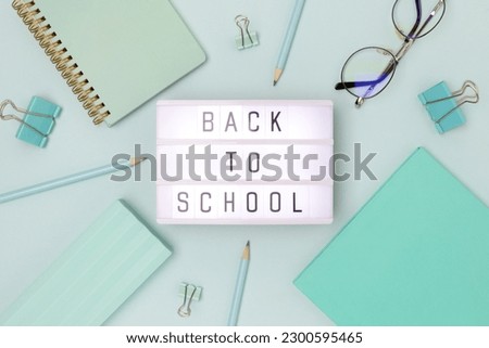 Back to school. Lightbox with letters and frame made of stationery on a blue background.