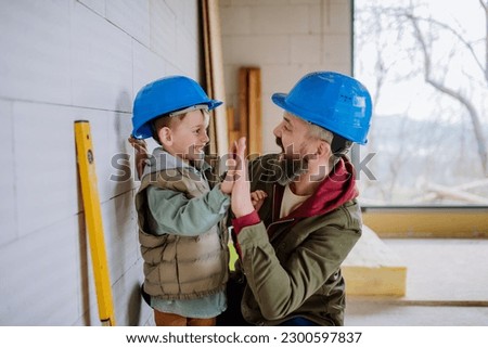 Father and his little son working on their unfinished house. Royalty-Free Stock Photo #2300597837