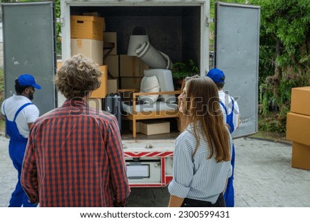 Happy couple with moving boxes at new house,Moving company employee checks boxes in a truck before sending them to the homeowner.