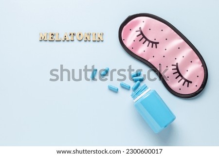 Blue bottle and pills, letters Melatonin and sleep mask on light grey background. Sleeping backdrop Concept melatonin, insomnia and good night. Top view Royalty-Free Stock Photo #2300600017