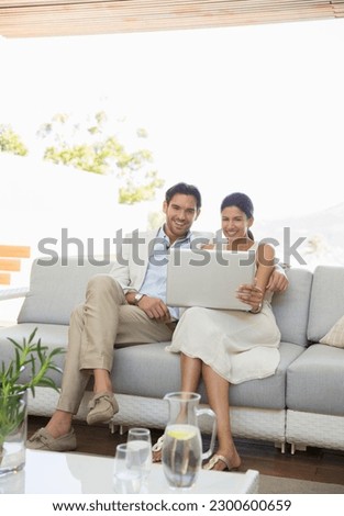 Couple using laptop together on sofa Royalty-Free Stock Photo #2300600659