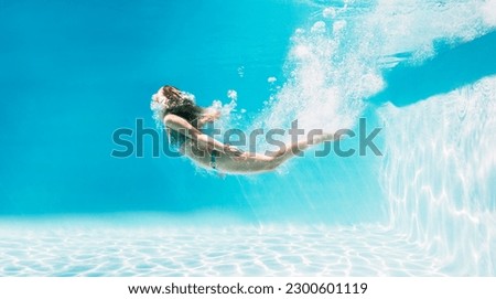 Woman swimming underwater in swimming pool Royalty-Free Stock Photo #2300601119