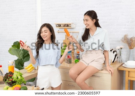 Asian two women wearing  sportswear eat healthy foods in kitchen. Young beautiful girl  happy and enjoy eating fruits healthy foods. Royalty-Free Stock Photo #2300605597