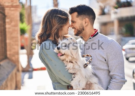 Man and woman holding dog standing together at street