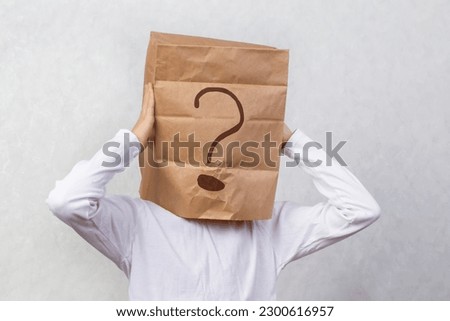 Anonymous man on a gray background with a cardboard box on his head with a drawn question mark. Problems and solutions. Getting answers.