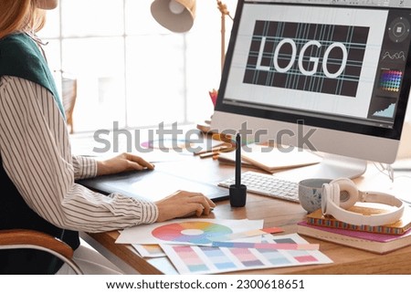 Female graphic designer working with tablet at table in office, closeup Royalty-Free Stock Photo #2300618651