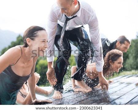 Fully dressed friends climbing out of swimming pool Royalty-Free Stock Photo #2300623341