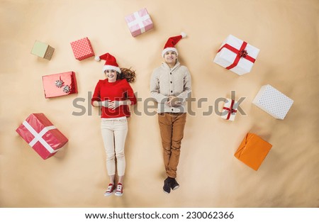 Happy young couple with Christmas presents against the beige background