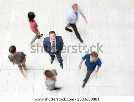 Businessman standing in busy office hallway