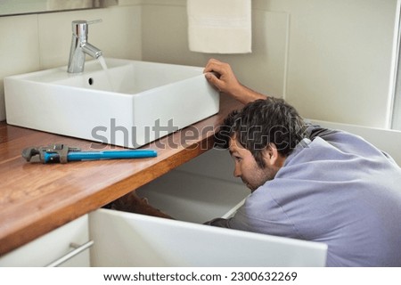 Plumber working under kitchen sink Royalty-Free Stock Photo #2300632269