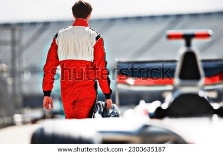 Racer carrying helmet on track Royalty-Free Stock Photo #2300635187