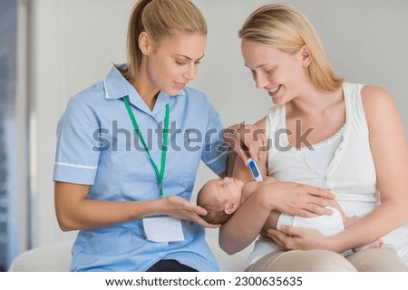 Mother and nurse taking newborn baby's temperature