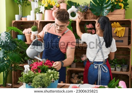 Man and woman florists watering plant working at flower shop Royalty-Free Stock Photo #2300635821