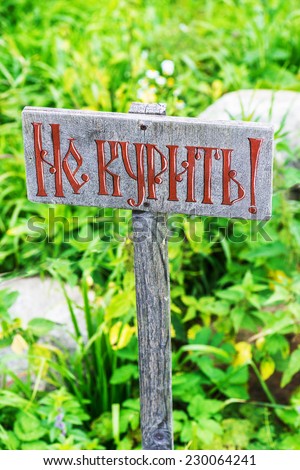 Nameplate "No smoking!" in Russian in summer city park.