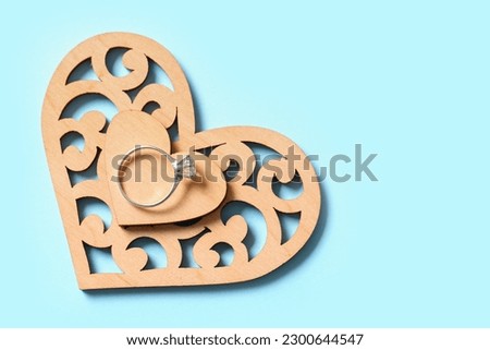 Silver engagement ring with wooden hearts on blue background Royalty-Free Stock Photo #2300644547