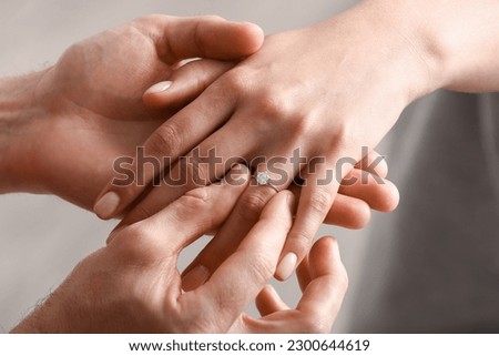 Man putting engagement ring on woman's finger, closeup Royalty-Free Stock Photo #2300644619