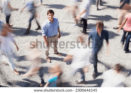 Portrait of smiling businessman surrounded by people rushing by Royalty-Free Stock Photo #2300646145
