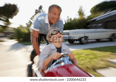 Time lapse view of father pushing son in go cart Royalty-Free Stock Photo #2300646233
