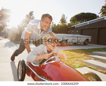 Father pushing son in go cart Royalty-Free Stock Photo #2300646359