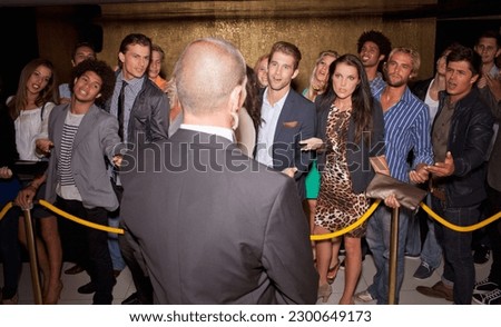Crowd gesturing to bouncer behind rope outside night club Royalty-Free Stock Photo #2300649173