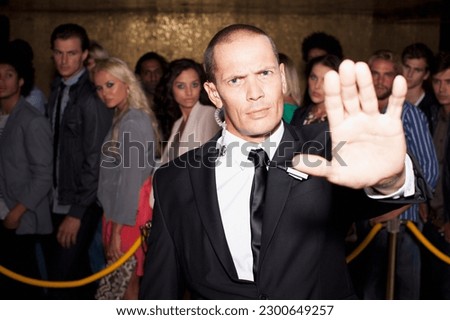 Portrait of bouncer with arm outstretched outside nightclub Royalty-Free Stock Photo #2300649257