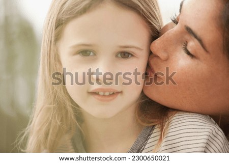 Close up portrait of mother kissing daughter's cheek