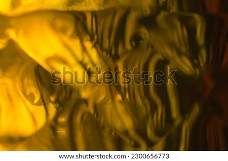 Beige-brown abstract background. An element of a plastic bottle with amber liquid on a sunny day.
