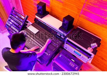 top view of asian professional music producer, sound engineer mixing a song in recording studio.music production, broadcasting concept