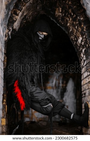 Surrealism theme: a man in a hannya mask, black kimono, and a katana in his hands in a winter forest. Surrealistic image of a man in a hannya half mask, kimono with a katana. Surreal samurai, ninja Royalty-Free Stock Photo #2300682575