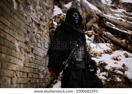 Surrealism theme: a man in a hannya mask, black kimono, and a katana in his hands in a winter forest. Surrealistic image of a man in a hannya half mask, kimono with a katana. Surreal samurai, ninja Royalty-Free Stock Photo #2300682591