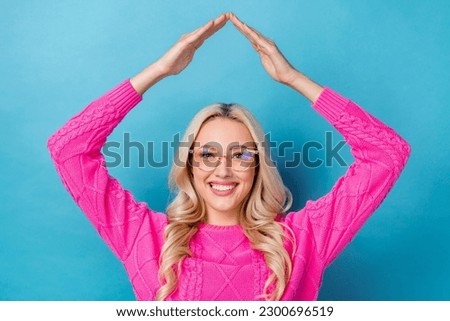 Photo of pretty cute lady wear pink sweater spectacles showing arms roof isolated blue color background