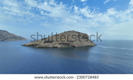 Aerial drone photo of Raftis island in bay of Porto Rafti with beautiful scattered clouds, Mesogeia, Attica, Greece