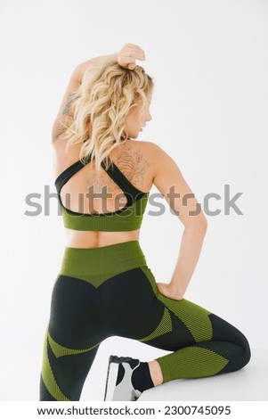rear view. an attractive blonde in a tracksuit posing with a white cube. the concept of a photo shoot for a trainer and advertising in social networks. fitness clothes.